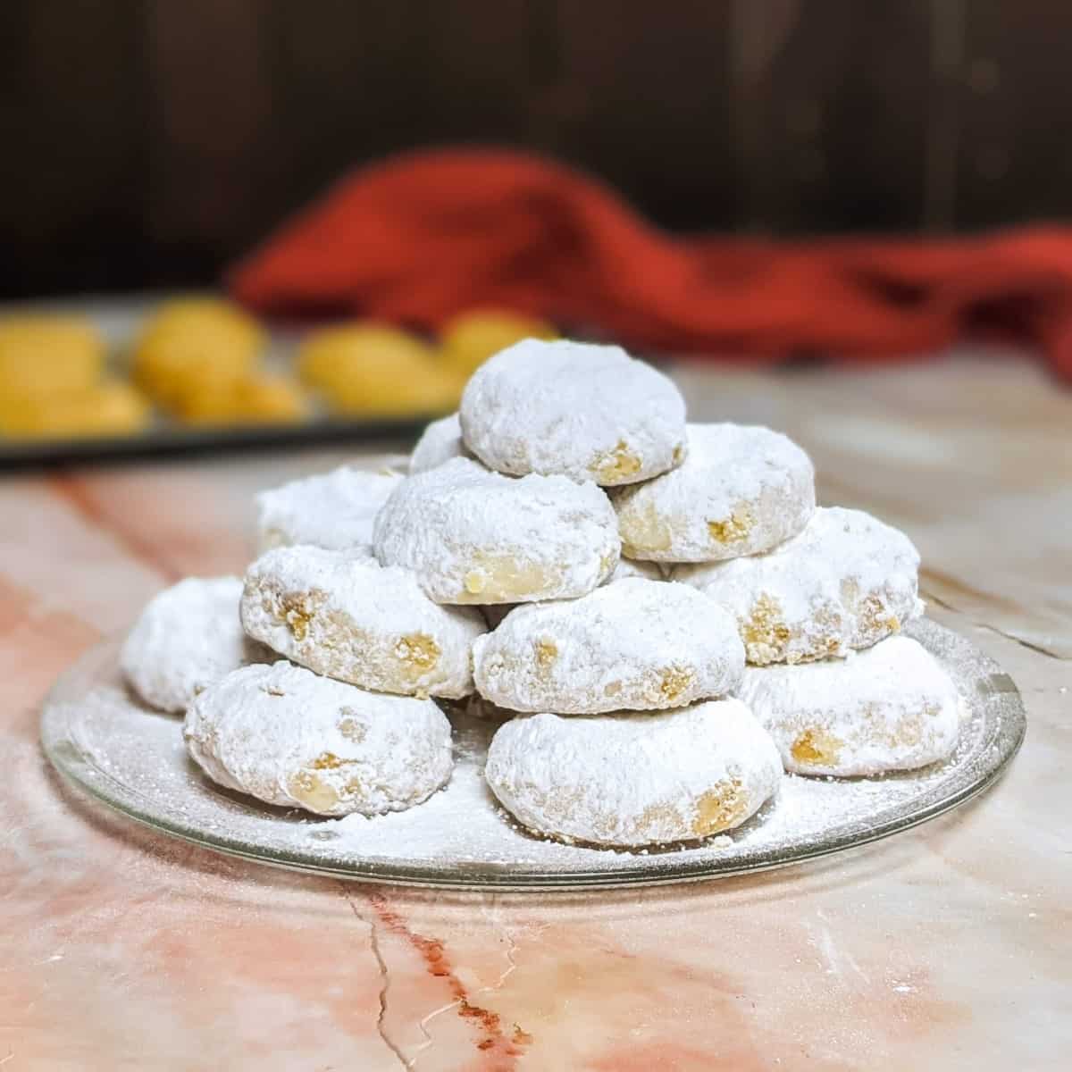 Kourabiedes served on a grey plate and dusting with powdered sugar.