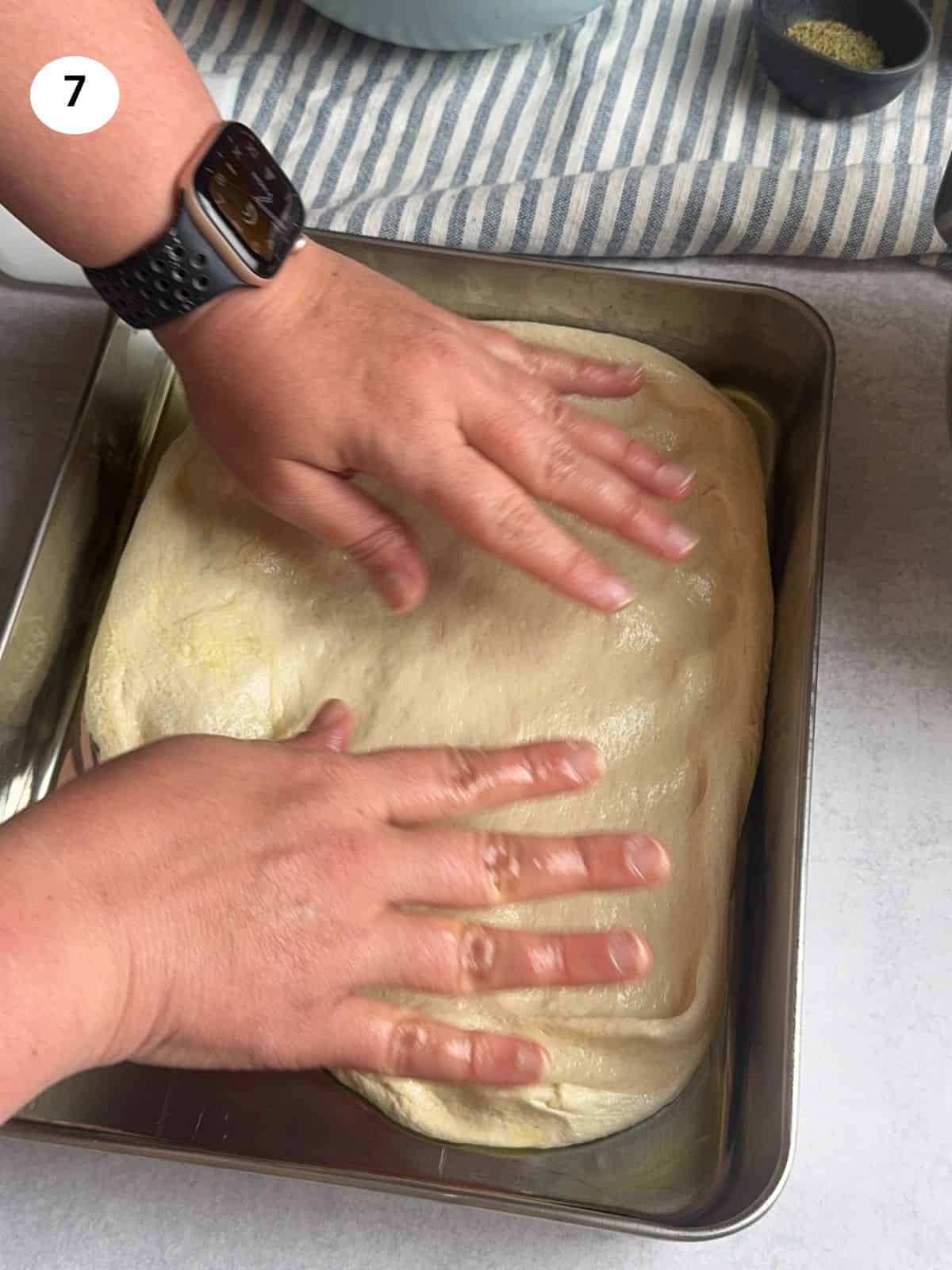 Spreading the dough in an oiled tray.