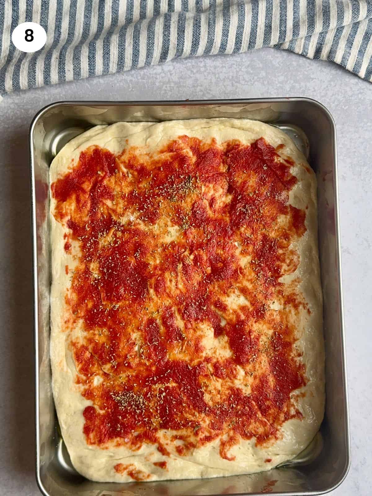 Tomato paste spread on top of dough.