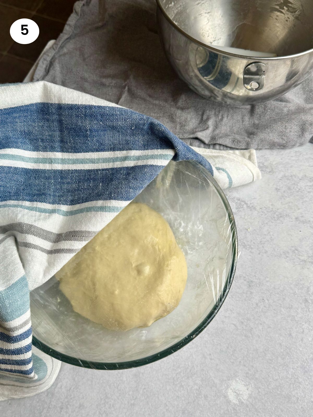 Covering the bowl with cling film and towel.