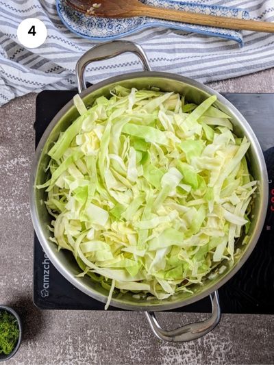 Adding the cabbage slices to the pot.