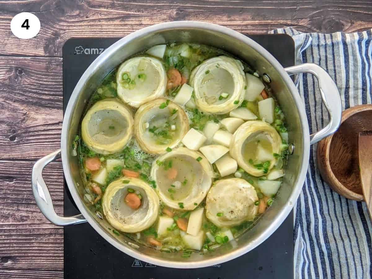 Artichoke stew in pot while being cooked.