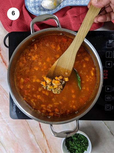 Adding the orzo pasta to the stew.