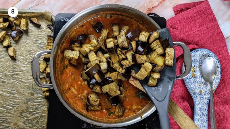 Adding the roasted eggplant cubes to the stew.