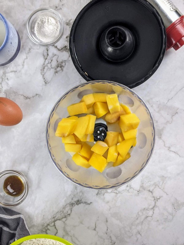 Adding mango and milk in food processor.