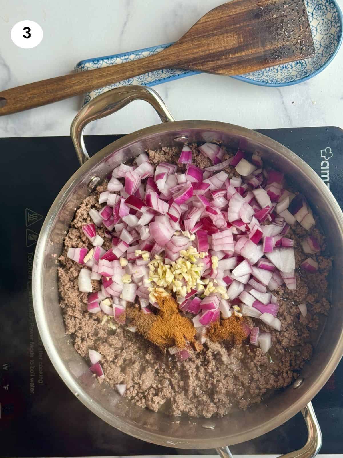 Adding the onion and spices to the pot.