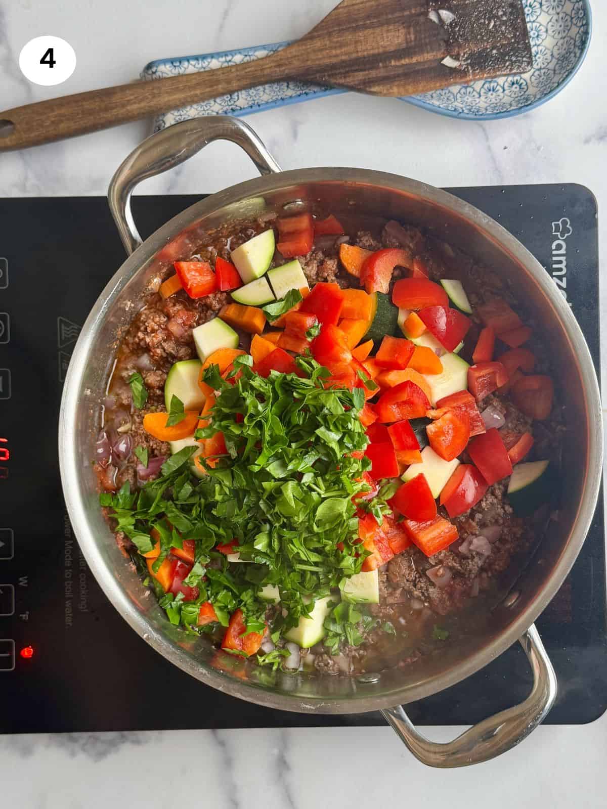 Adding the vegetables and parsley to the pot.