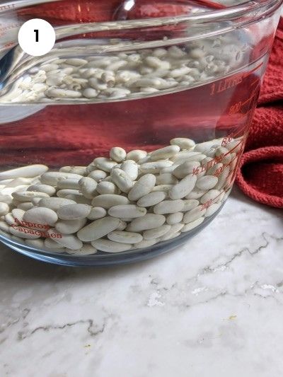 Soaking white beans in water overnight.