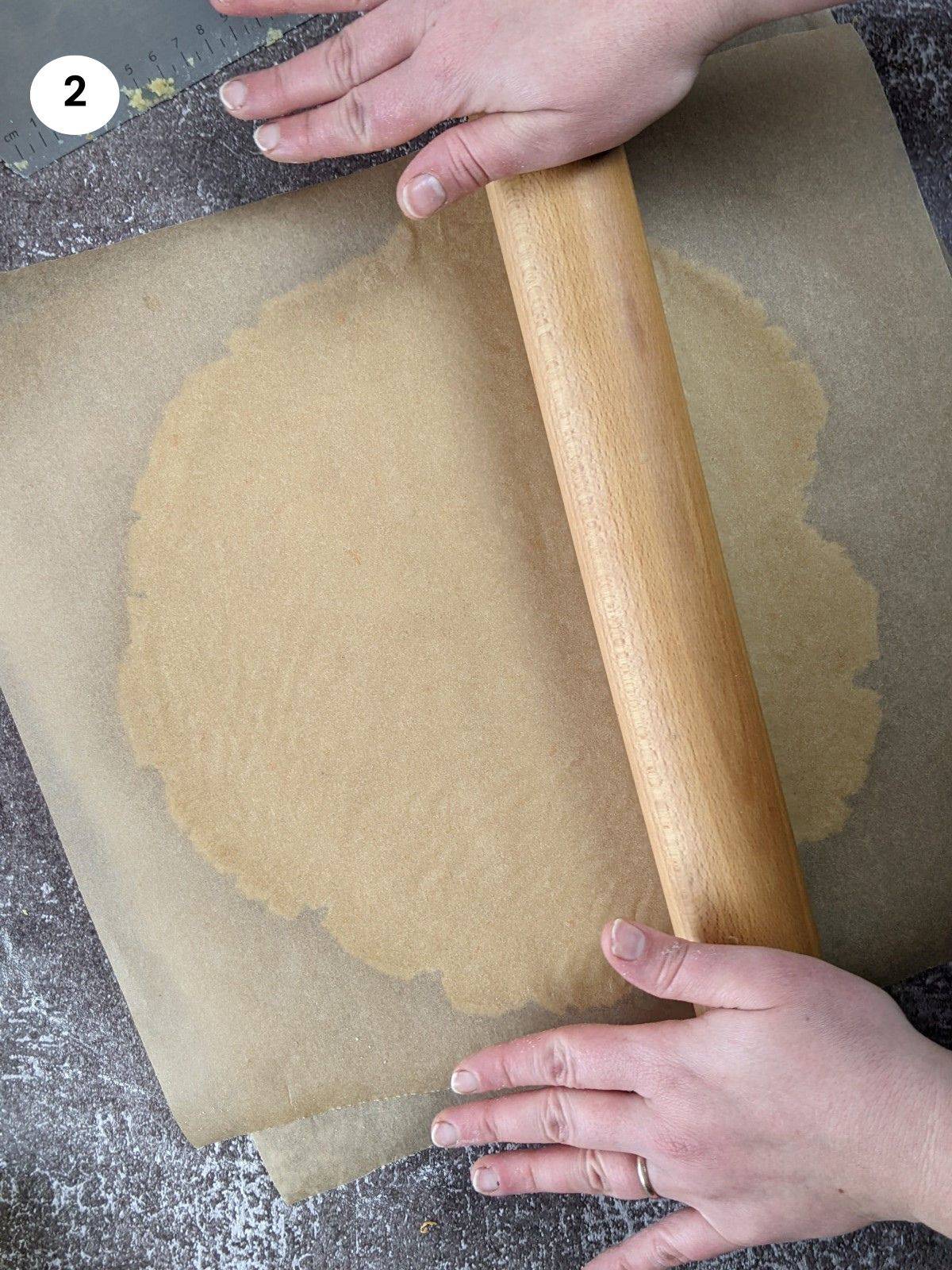 Rolling the dough into a circle between parchment paper