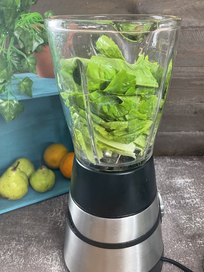Adding lettuce in blender for green pear smoothie.