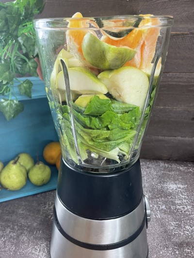 Adding orange in blender for green pear smoothie.