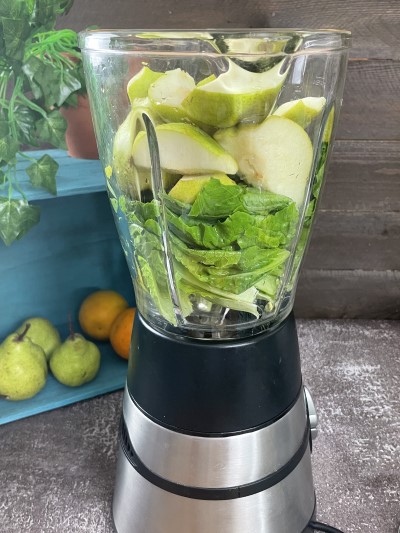 Adding pear in blender for green pear smoothie.