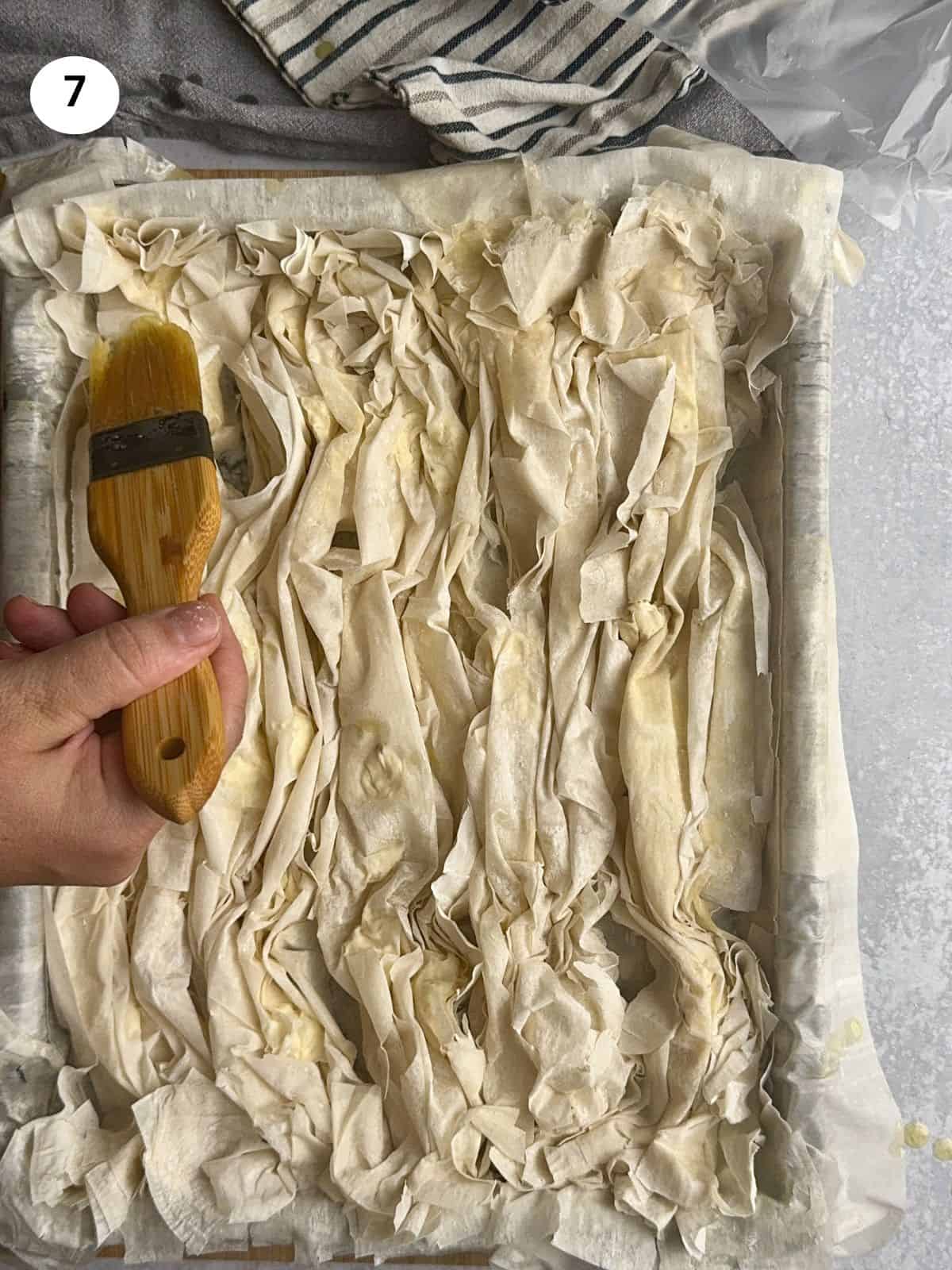 Brushing the top phyllo sheets with butter.