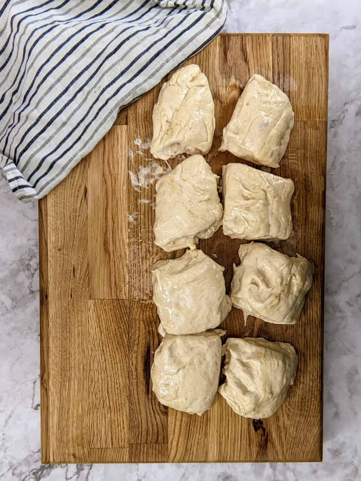 Dough on a wooden surface cut in 8 equal pieces.