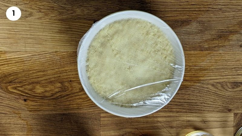 Adding couscous to a bowl and covering with hot water.