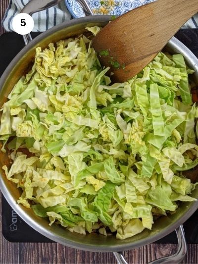 Adding the cabbage slices to the pot.