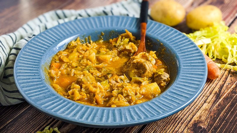 Cabbage and pork stew served in blue bowl.