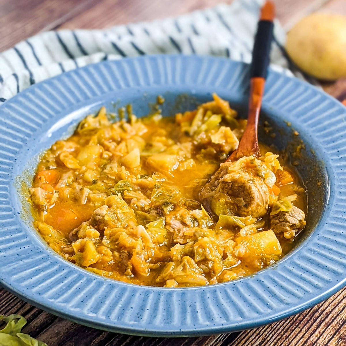 Cabbage and pork stew served in a blue bowl.