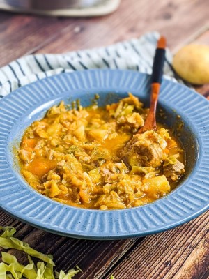 Cabbage and pork stew served in a blue bowl.