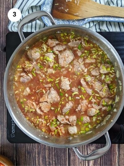 Adding the tomato puree and leeks to the pot.