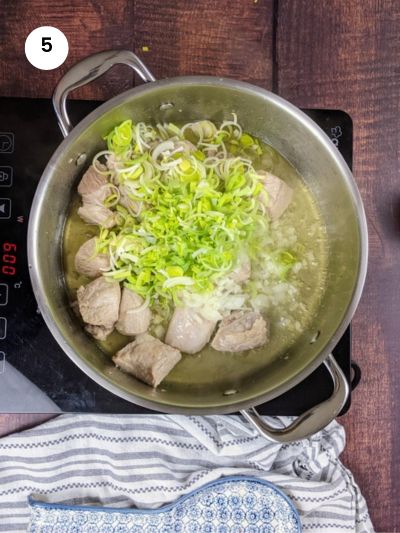 Adding the chopped onion and leek to the pot.