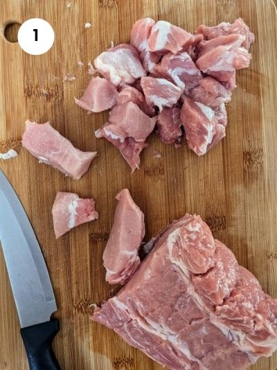 Chopped pork meat into cubes for skewers.