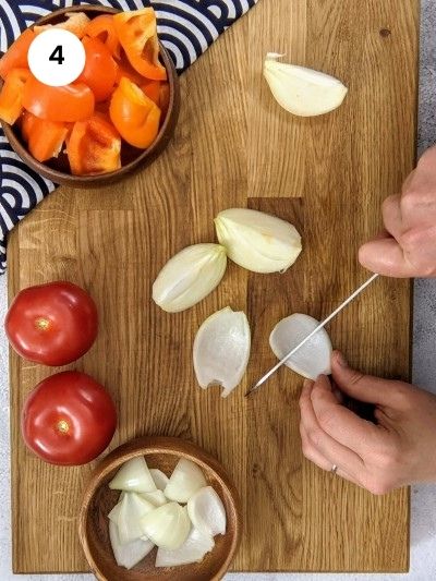 Cutting onion slices for assembling the pork skewers.