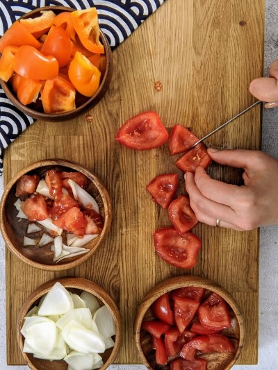 Cutting tomato slices for assembling the pork skewers.