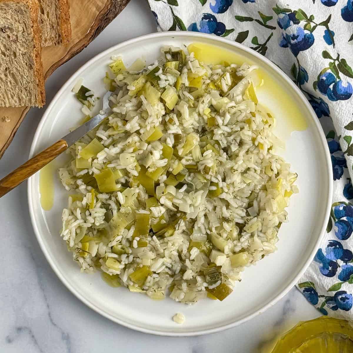 Prasorizo served on a white plate with olive oil bottle at the back