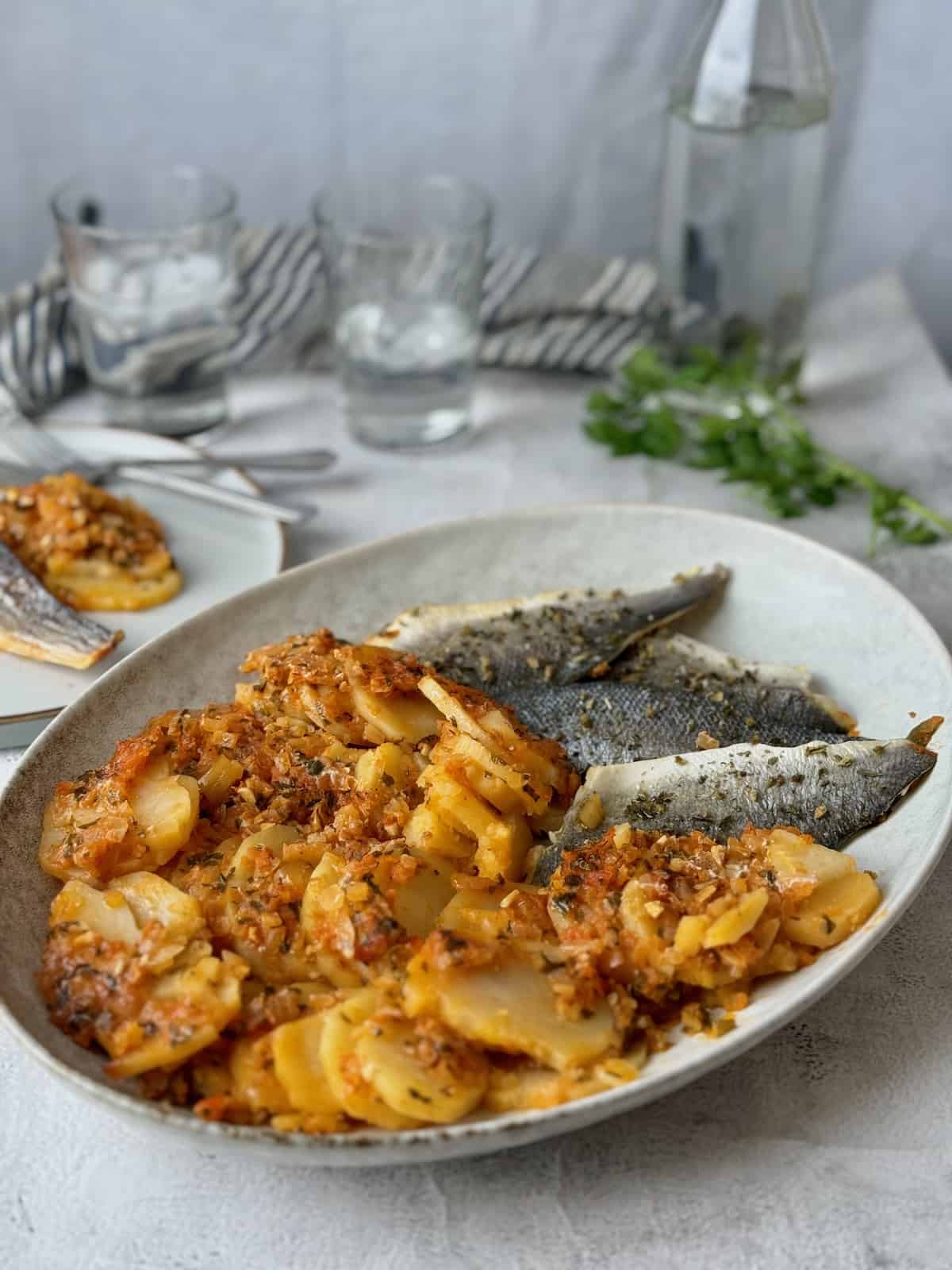 Fish plaki served on a big serving plate with potatoes.