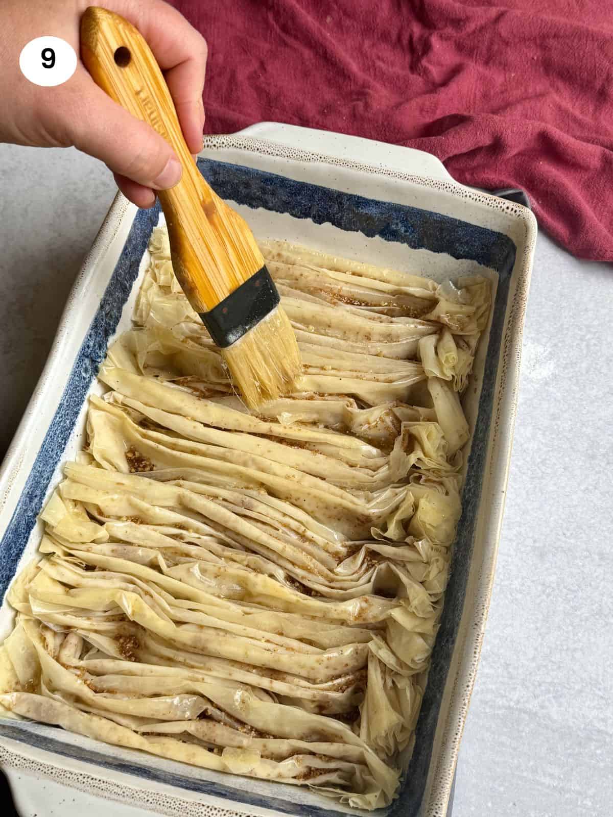 Brushing the top of the baked phyllo sheets with the remaining butter.