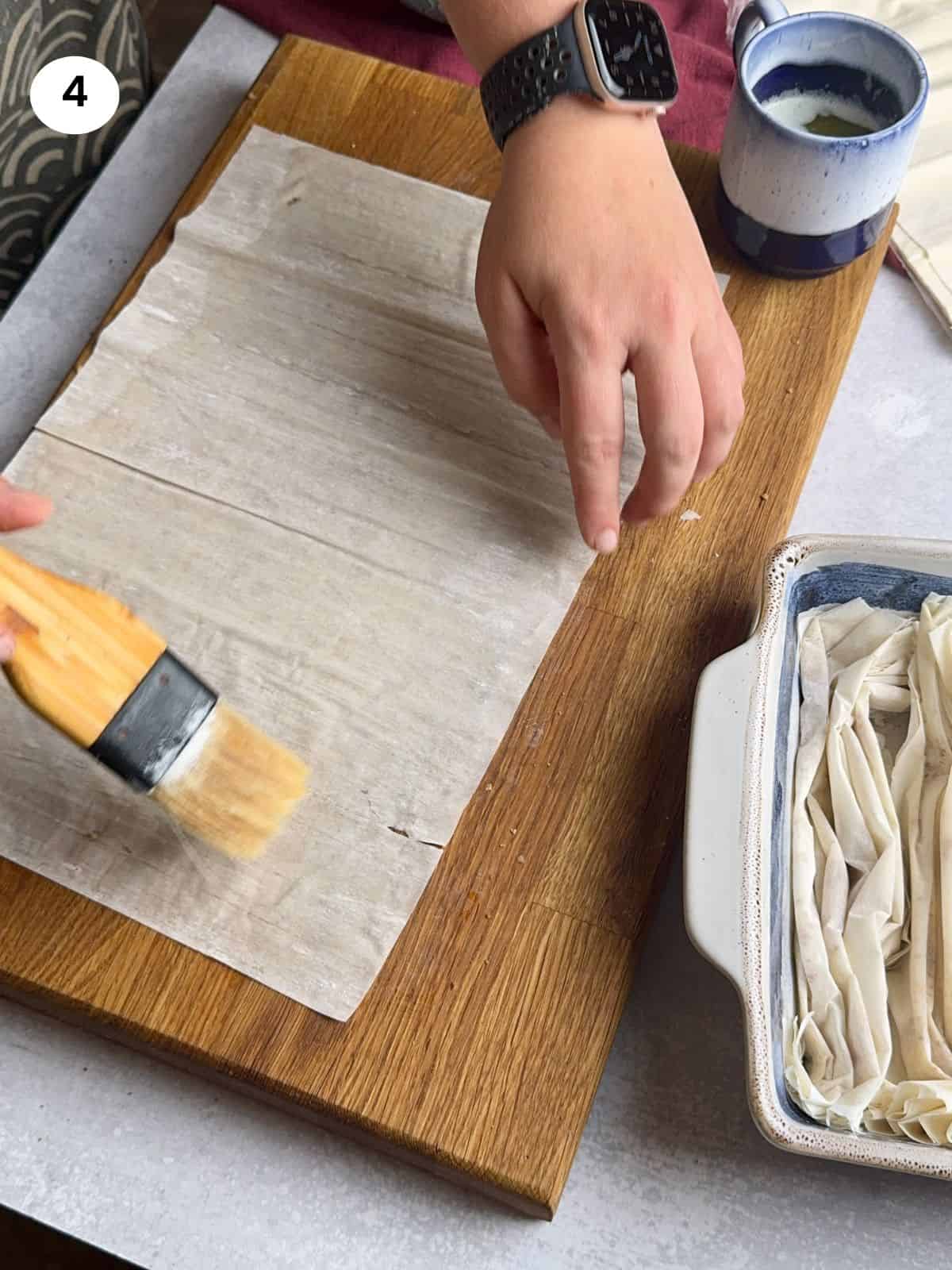 Brushing a phyllo sheet with butter.
