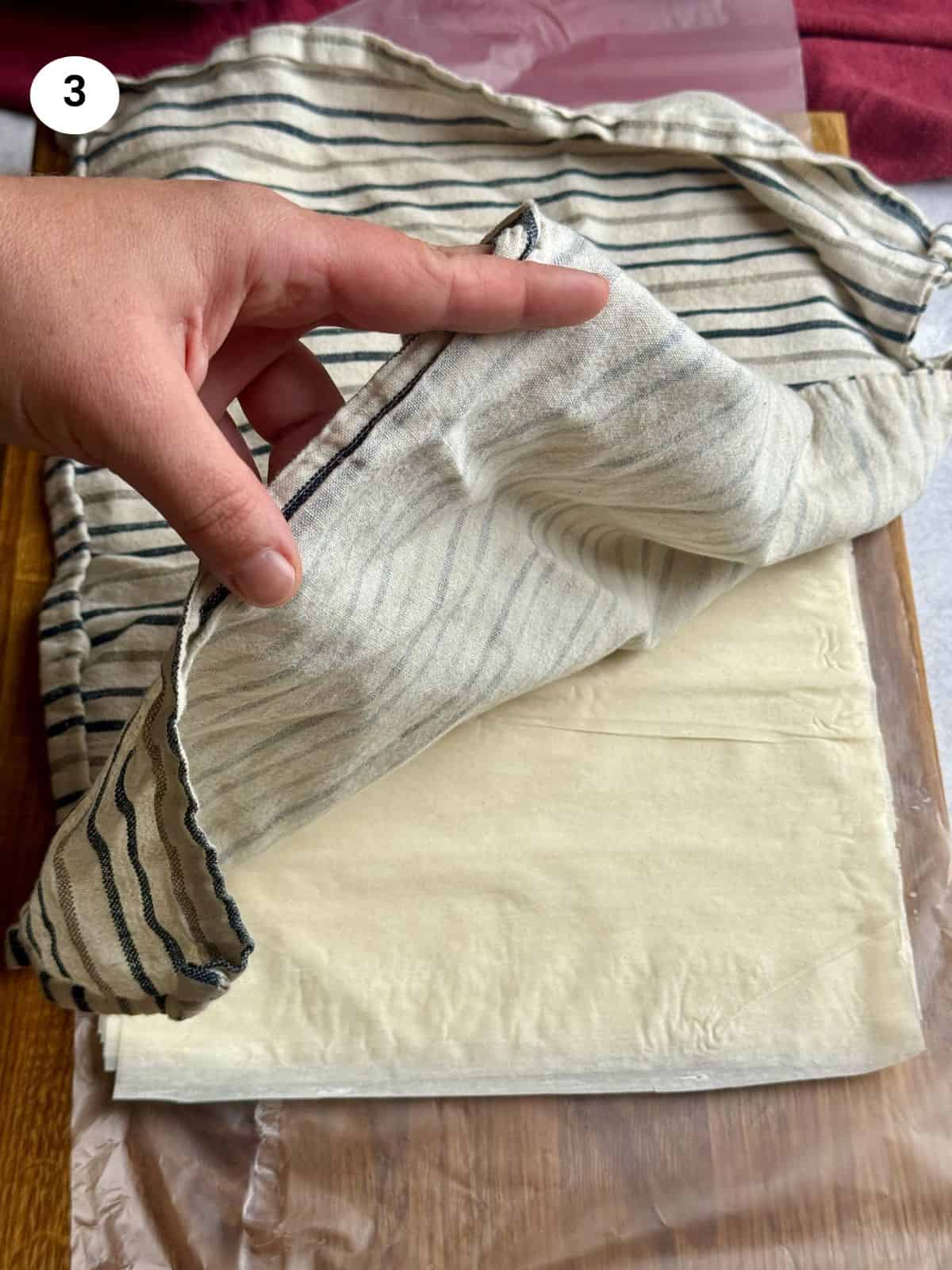 Covering phyllo sheets to prevent them from drying.