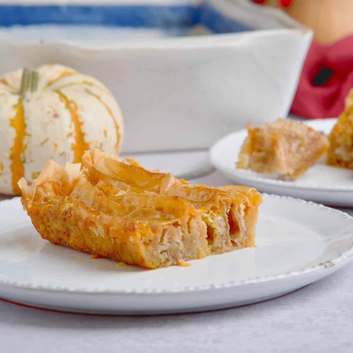 Crinkle pumpkin phyllo pie slices next to tray with pie.