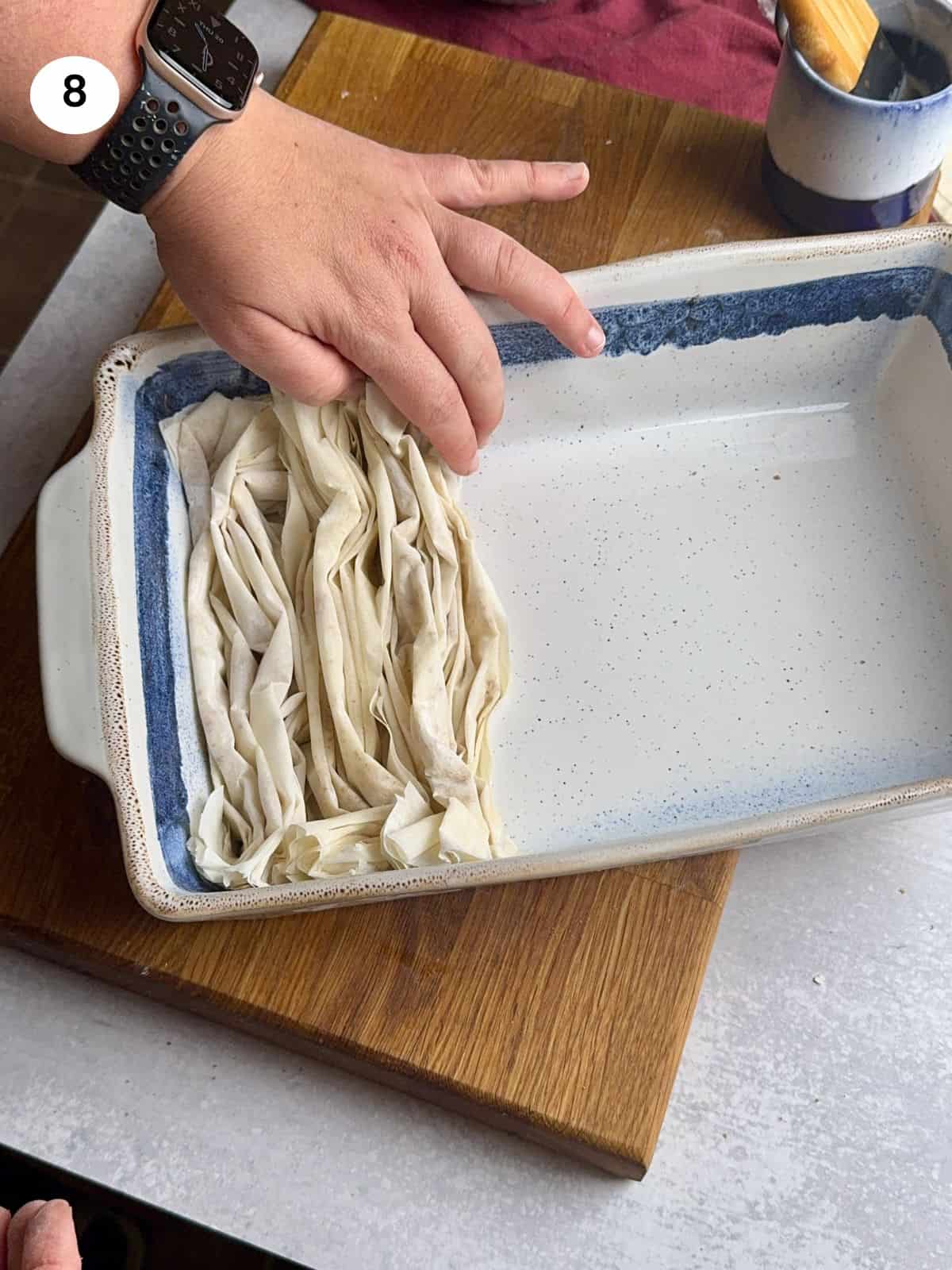 Placing the folded phyllo sheets in a tray.