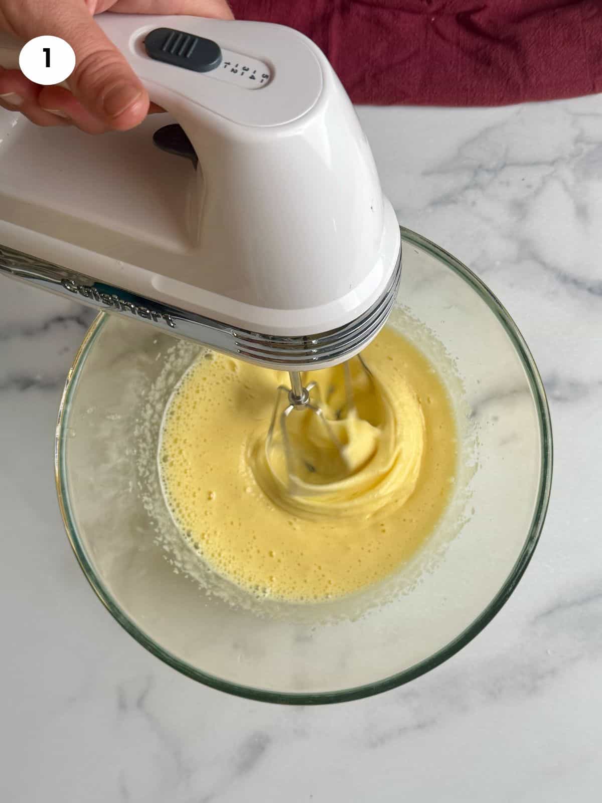 Mixing the eggs and sugar in glass bowl until fluffy.