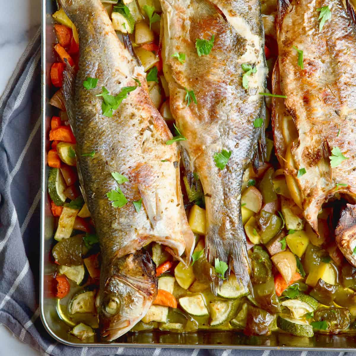 Branzino fish with vegetables in a tray.