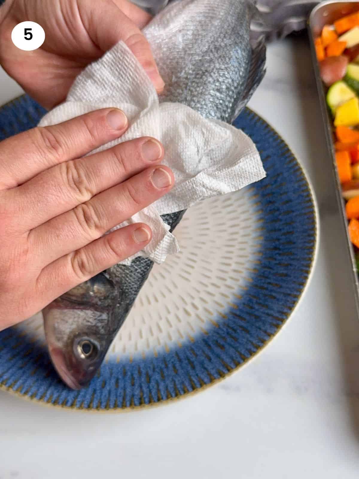 Pat drying the fish with a paper towel.