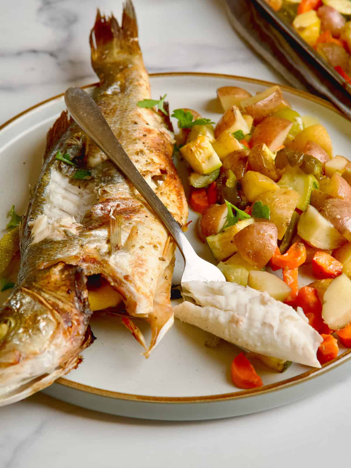 Branzino with veggies on a plate.