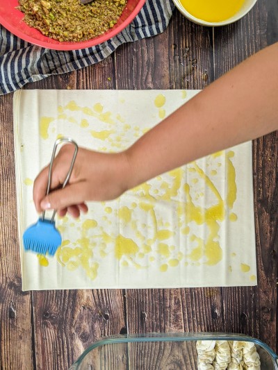 Drizzling butter on the filo pastry.