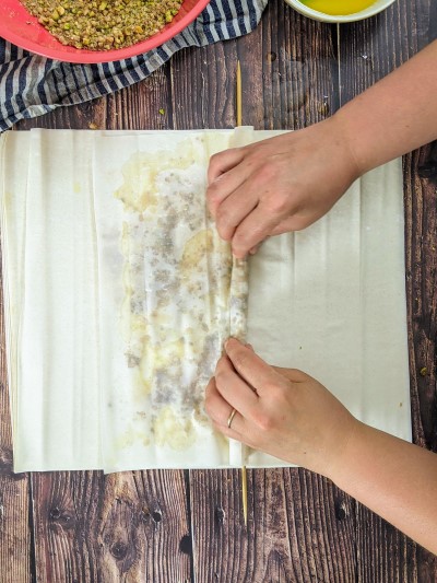 Start rolling filo pastry into a long baklava roll.