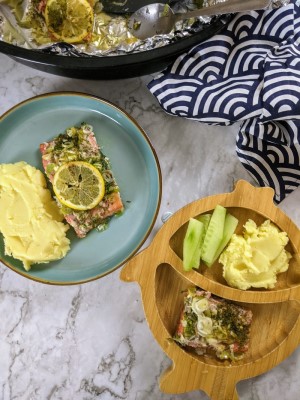 Salmon fillet served with lemon on top and mash on the side in an adult and a toddler bamboo plate