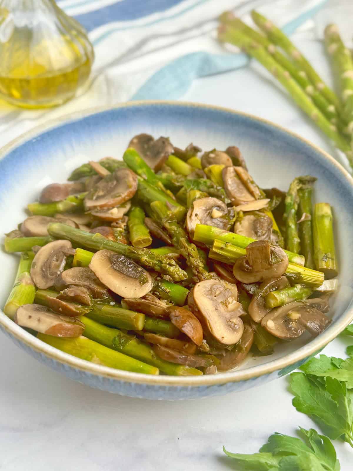 Sauteed asparagus and mushrooms served in a white bowl.
