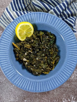 Sautéed Kale served in blue bowl with a slice of lemon