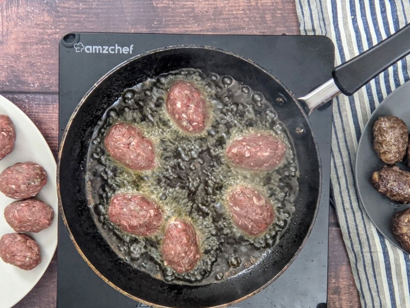 Shallow frying the meatballs.