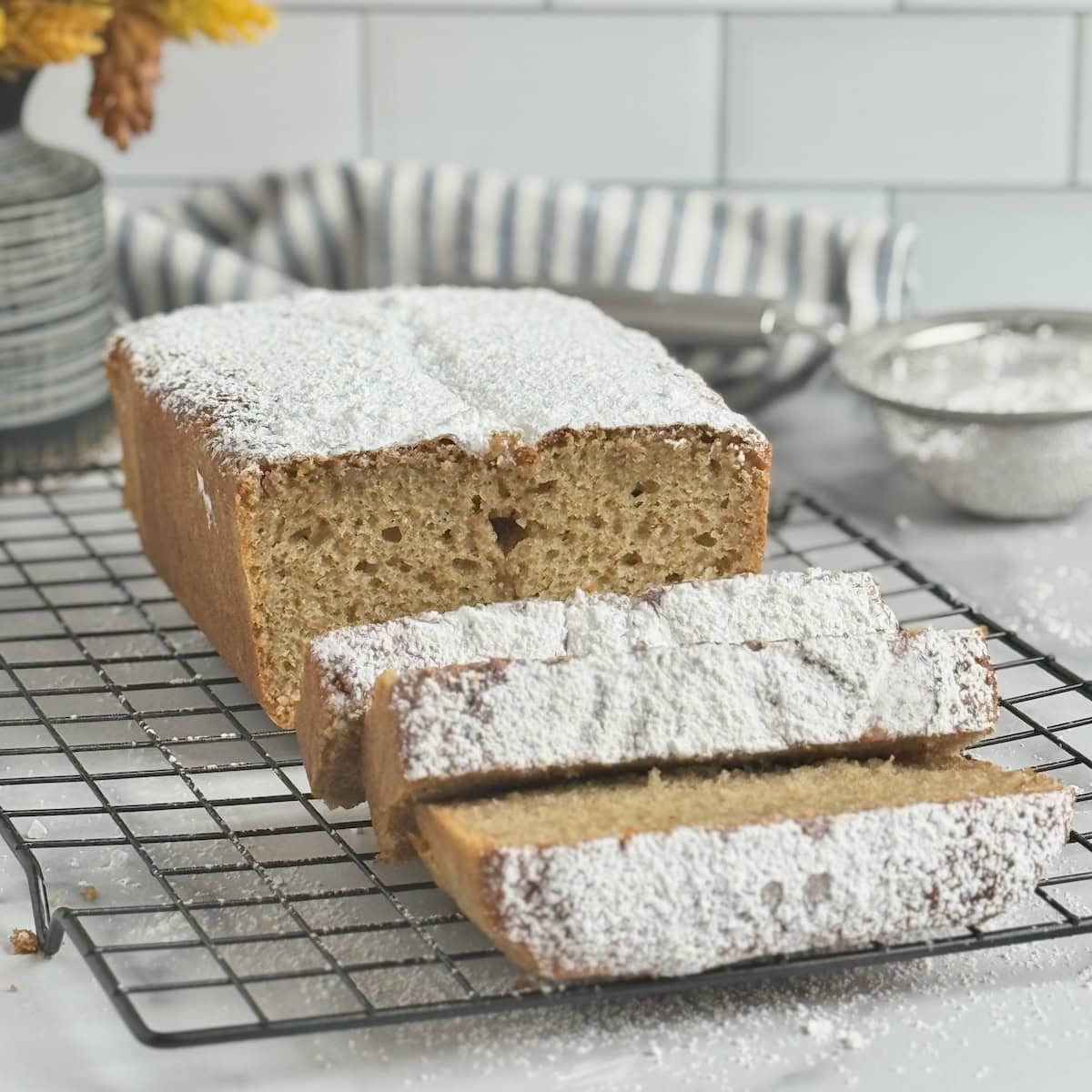 Greek yogurt spiced loaf cake dusted with powdered sugar on a wire rack.