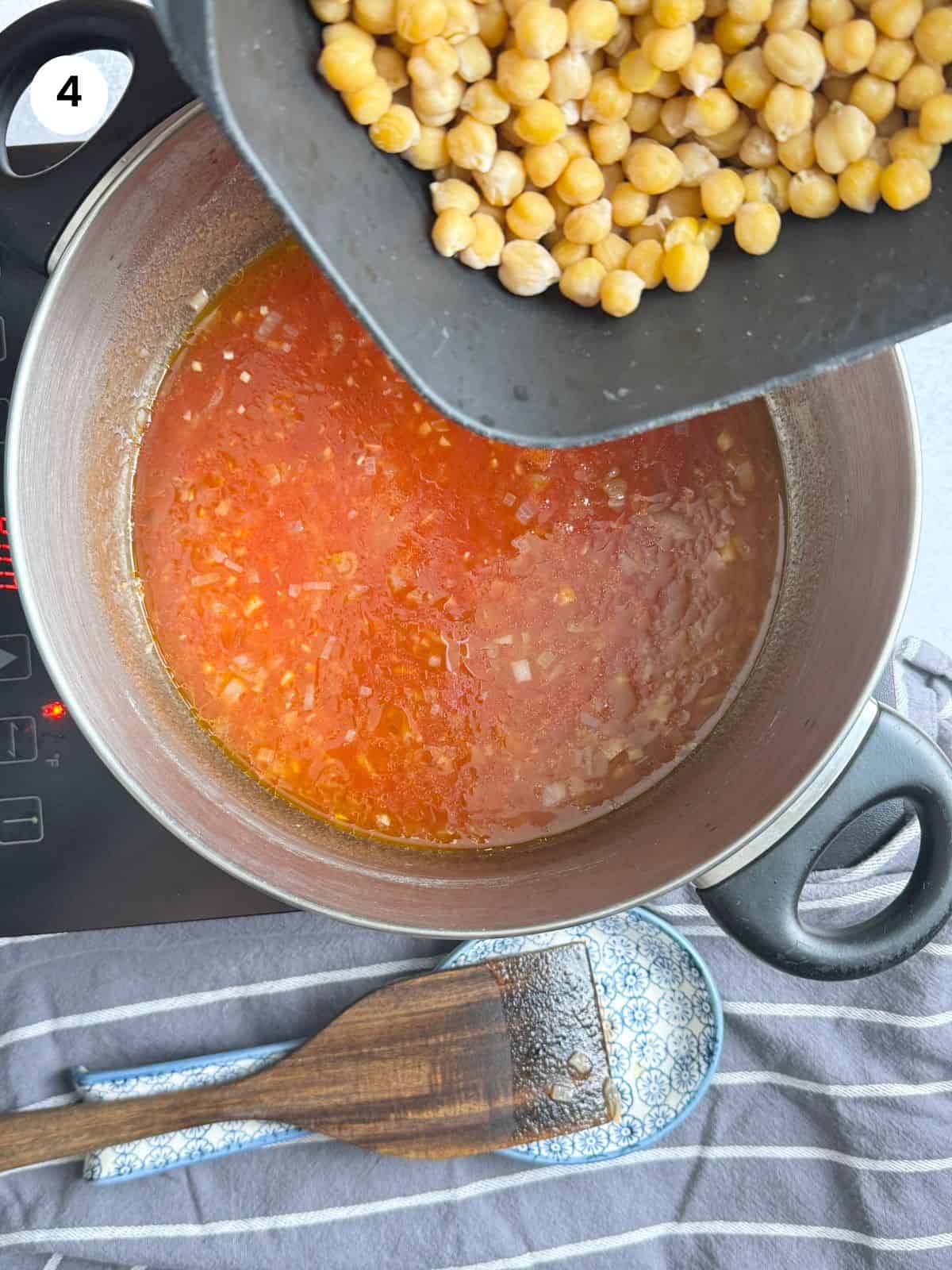 Adding the chickpeas to the pot with tomato sauce.