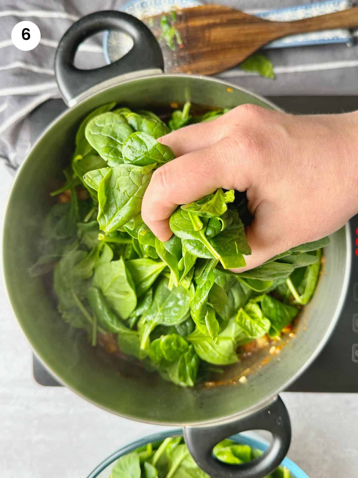 Adding the fresh spinach to the pot.