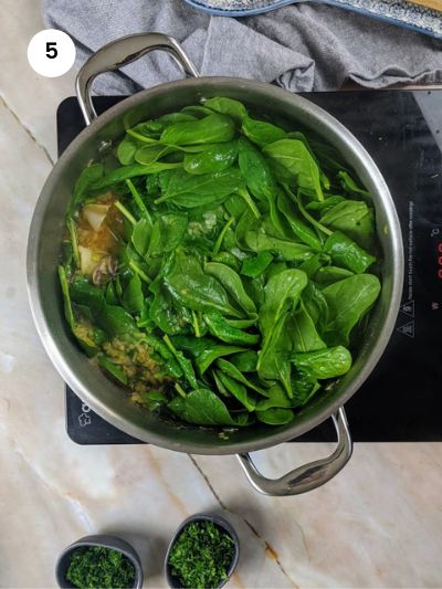 Adding the spinach and green onions to the squid stew.