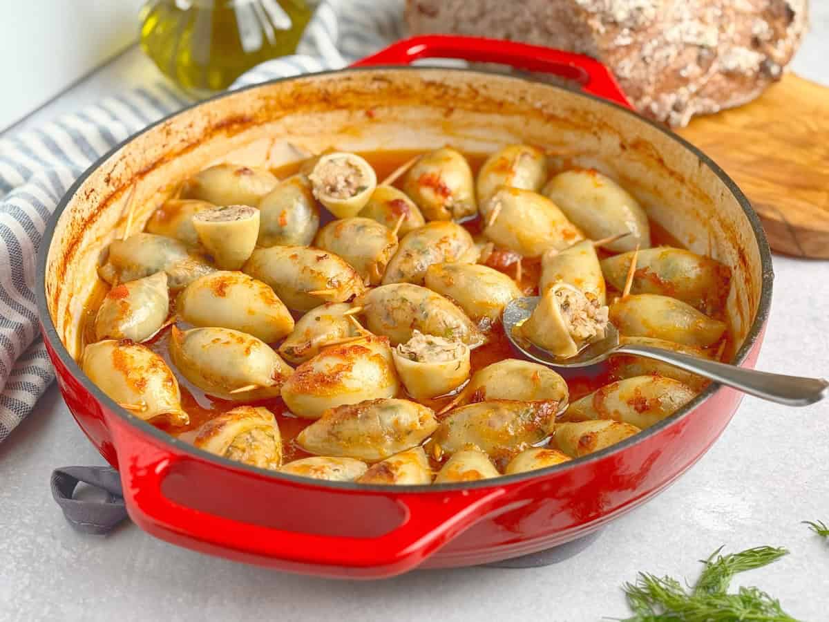 Stuffed calamari in tomato sauce in a red cast iron pan.